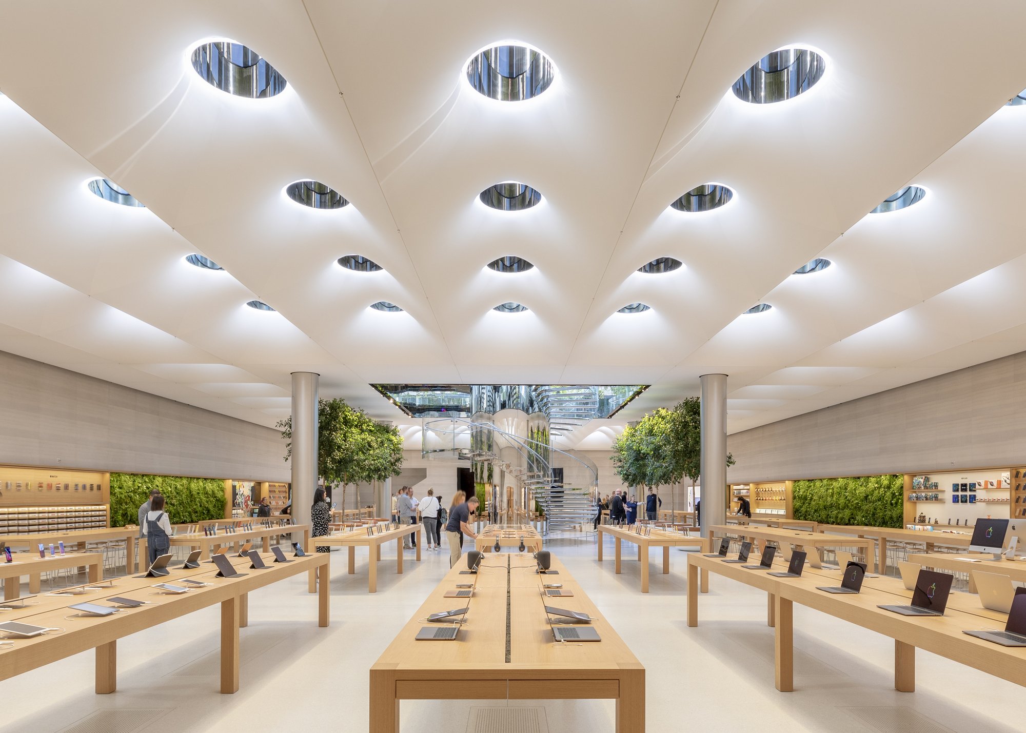 An Apple Store bustling with people engaged in shopping and product demonstrations in a lively retail atmosphere.