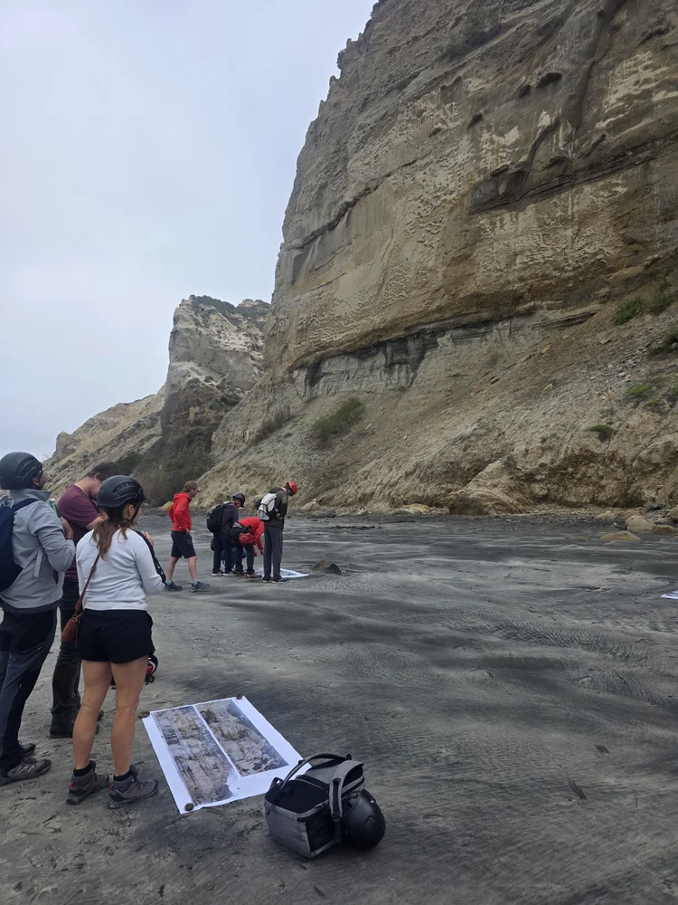 Group walking beneath tall sea cliff