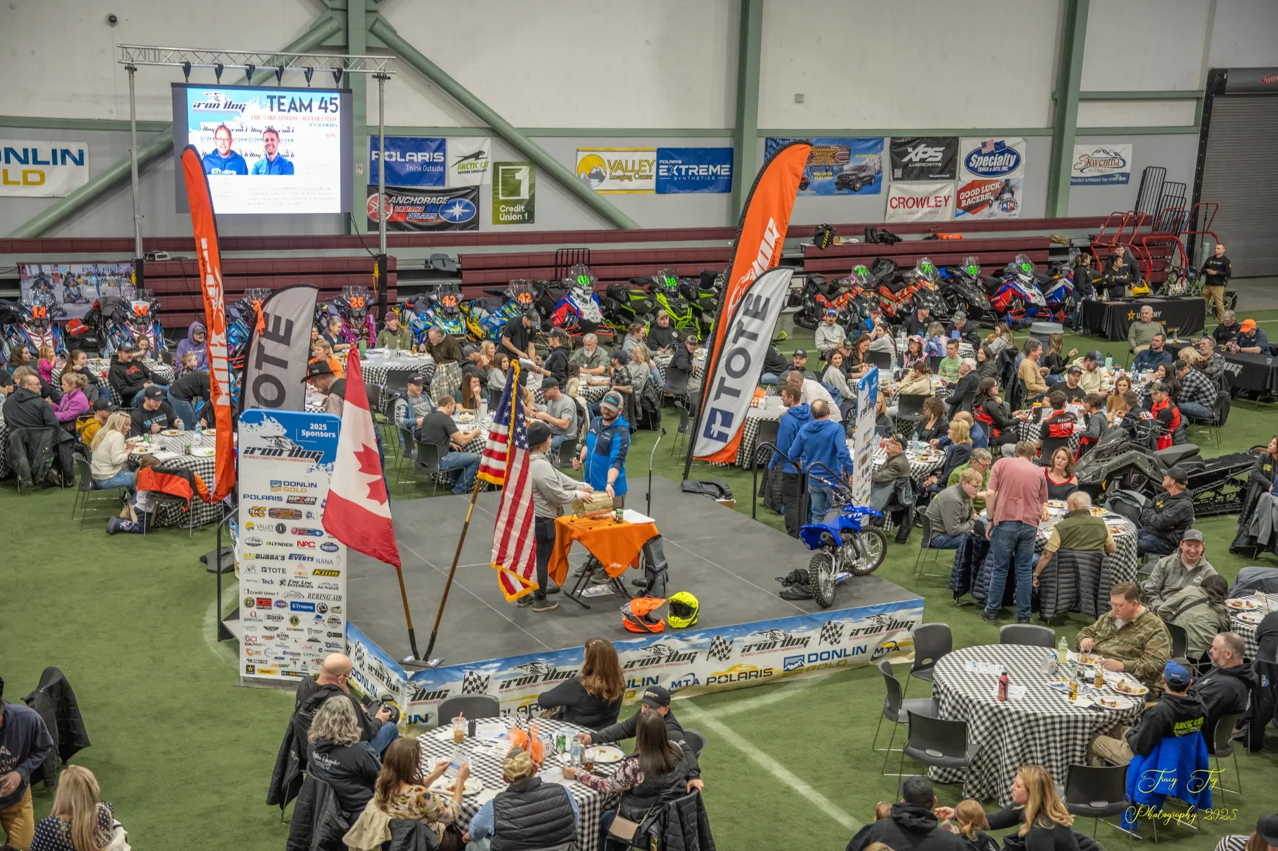 Iron Dog Racer Draw Banquet - crowd gathered at tables with snowmobiles on display