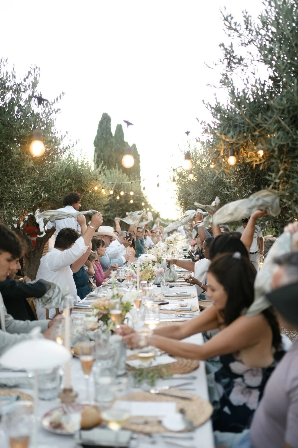 Guests lifting napkins around the long wedding dinner table.