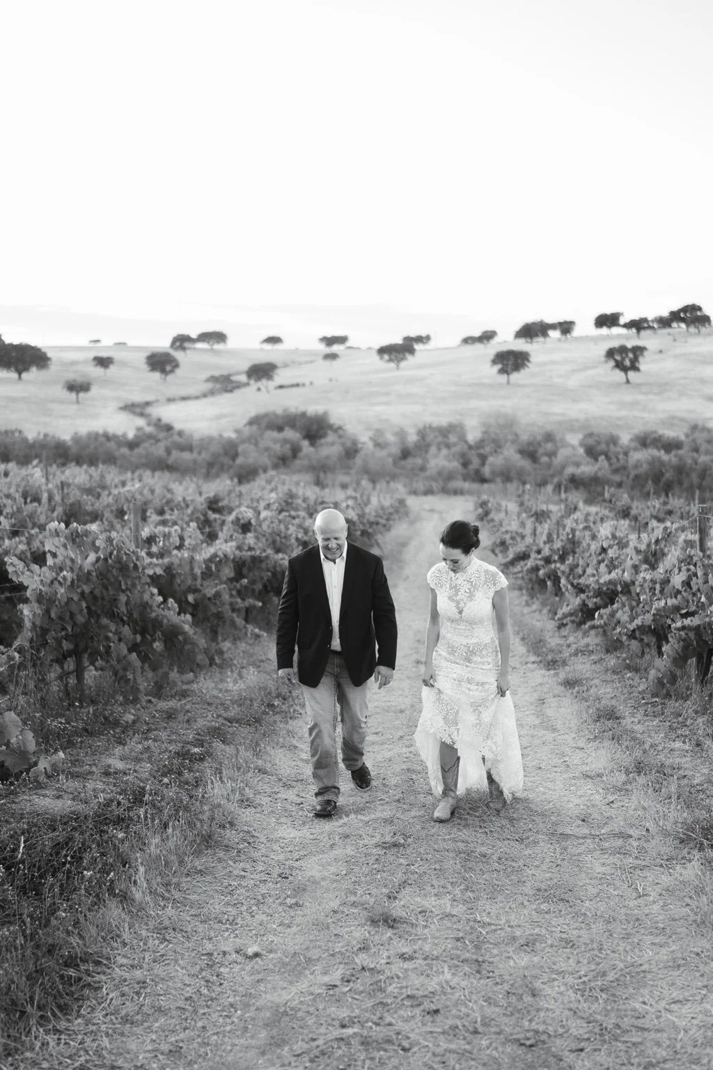 Black and white portrait of Joanna and Greg walking through the vineyard.