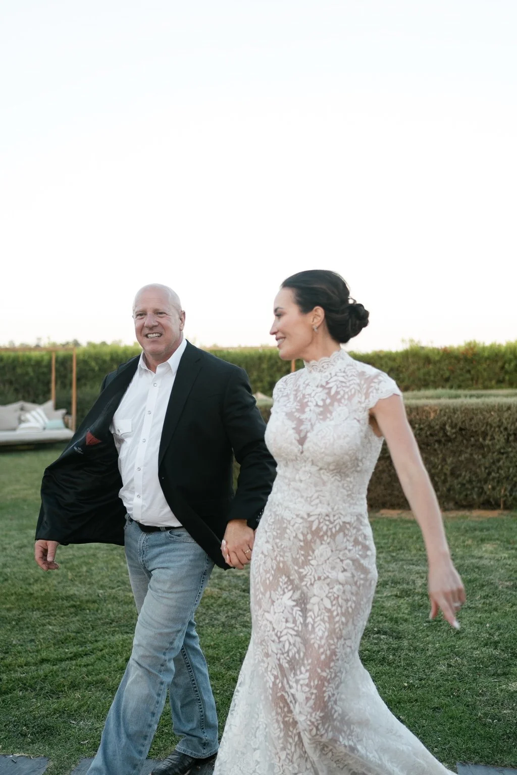 Joanna and Greg smiling as they walk beside the vines.