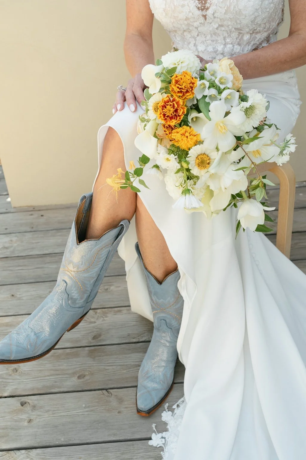 Joanna’s white and orange bouquet, lace dress and blue cowboy boots.
