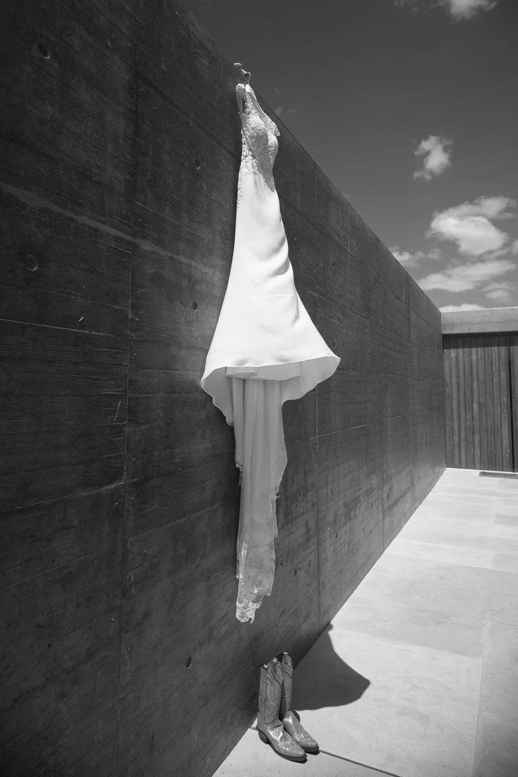 Black and white photograph of Joanna’s wedding dress and cowboy boots.