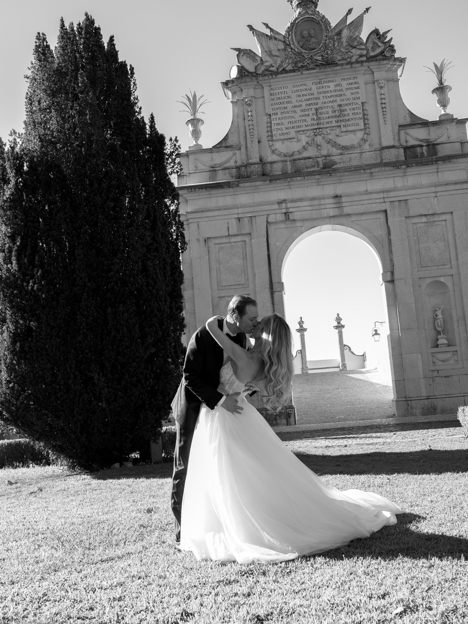 Jennifer and Trevor kissing beneath the palace arch in black and white