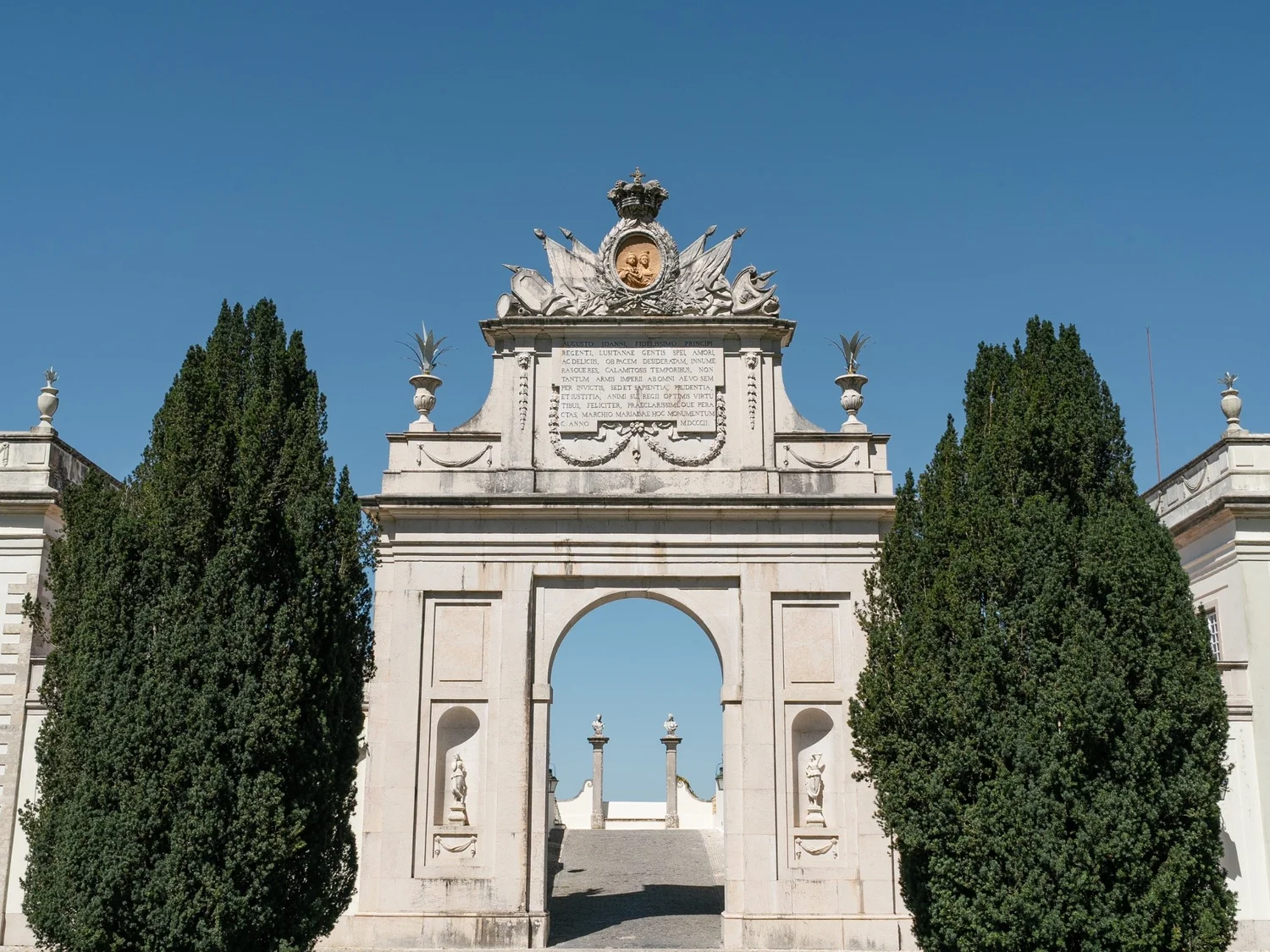 The monumental stone arch at Palácio de Seteais beneath a blue sky