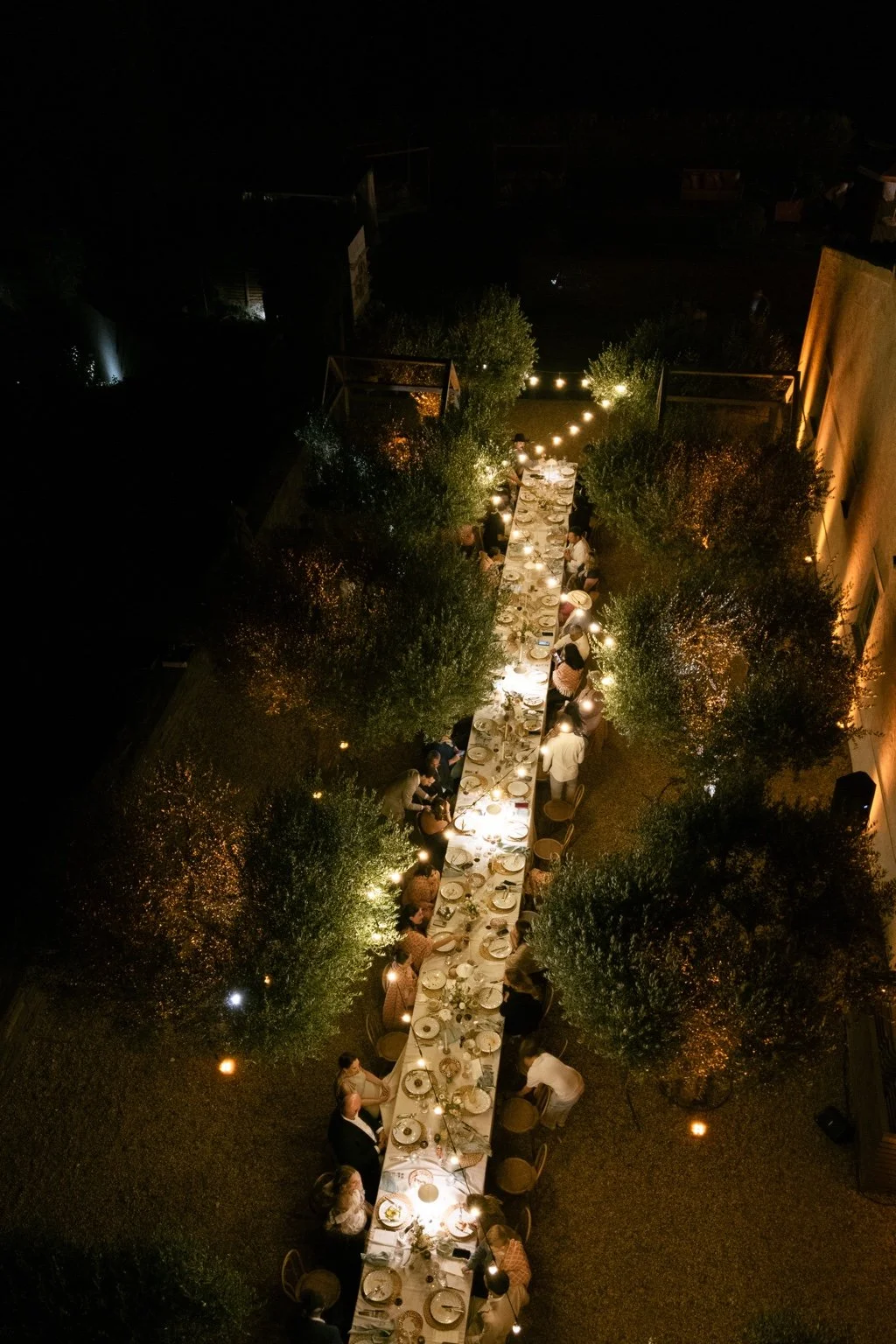 Aerial night view of the illuminated long wedding dinner table.