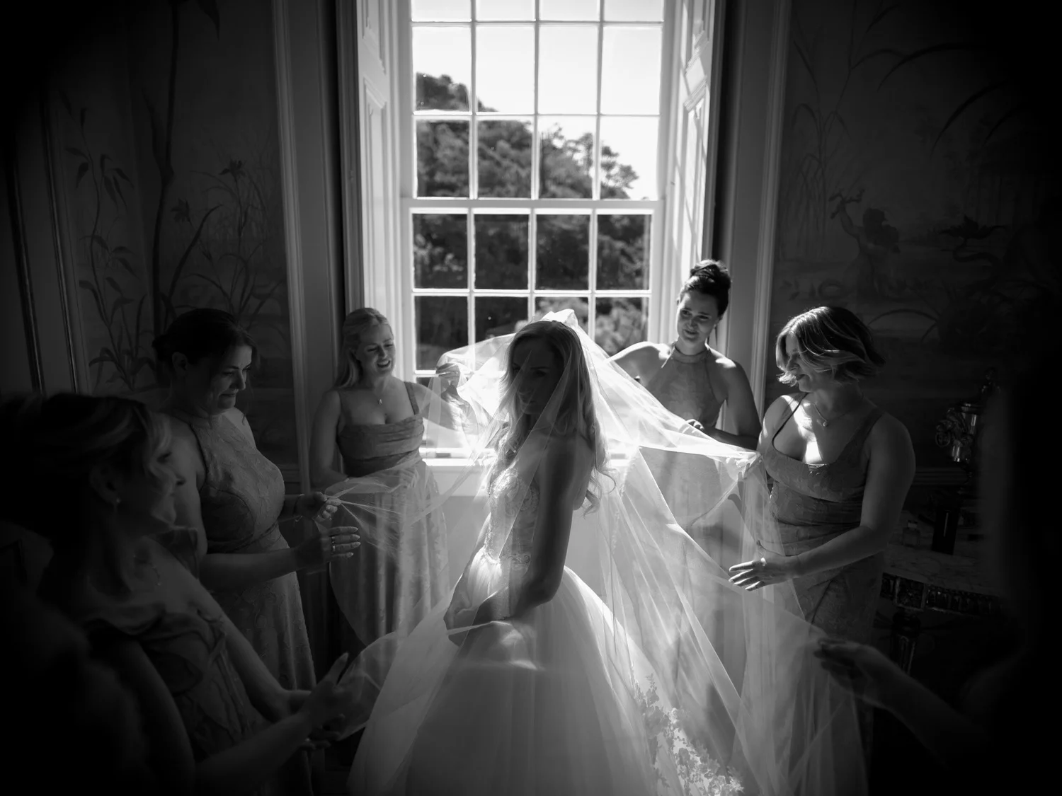 Jennifer getting ready beside a tall palace window, photographed in black and white