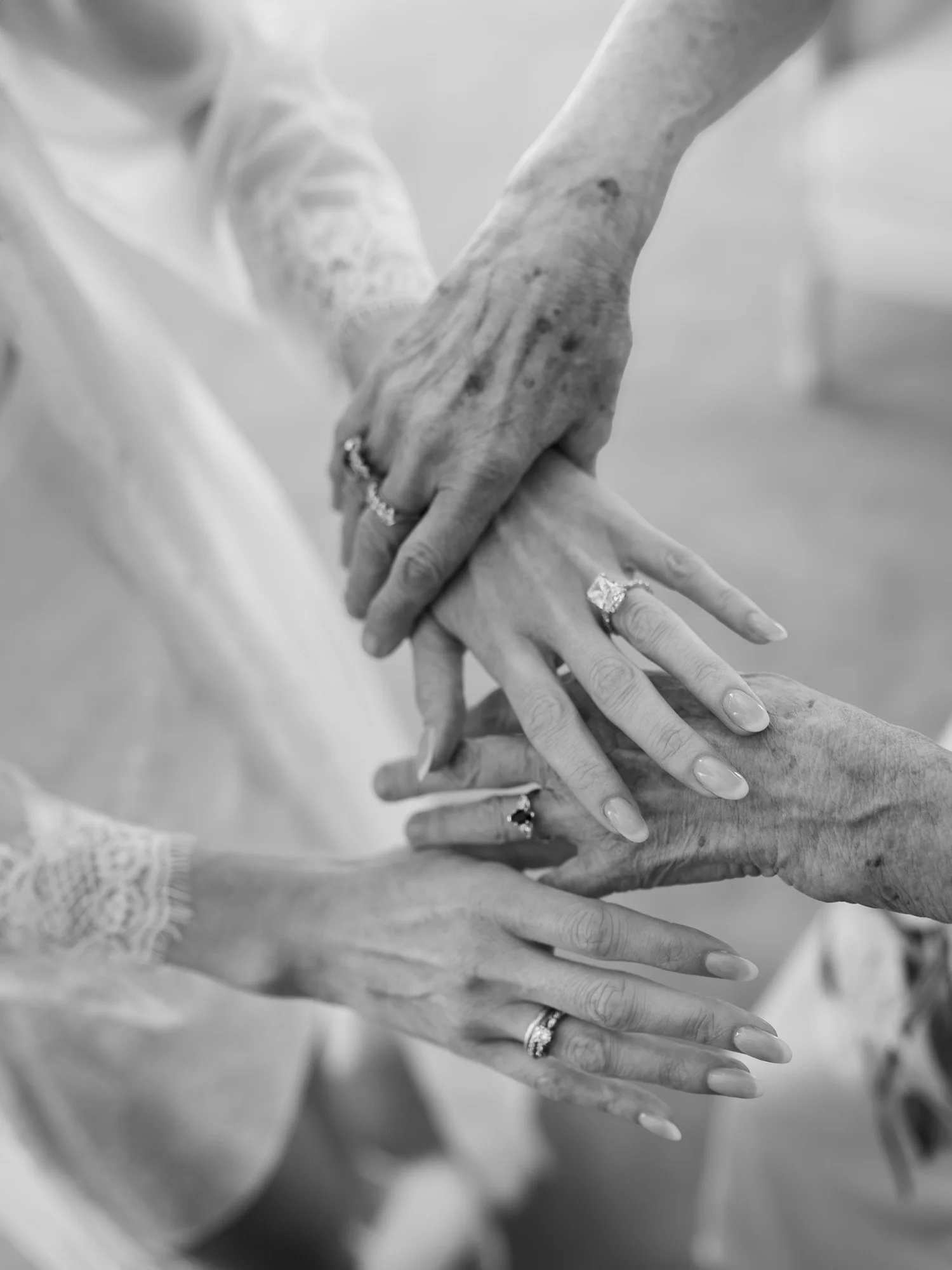 Black-and-white detail of hands and a wedding ring during bridal preparations