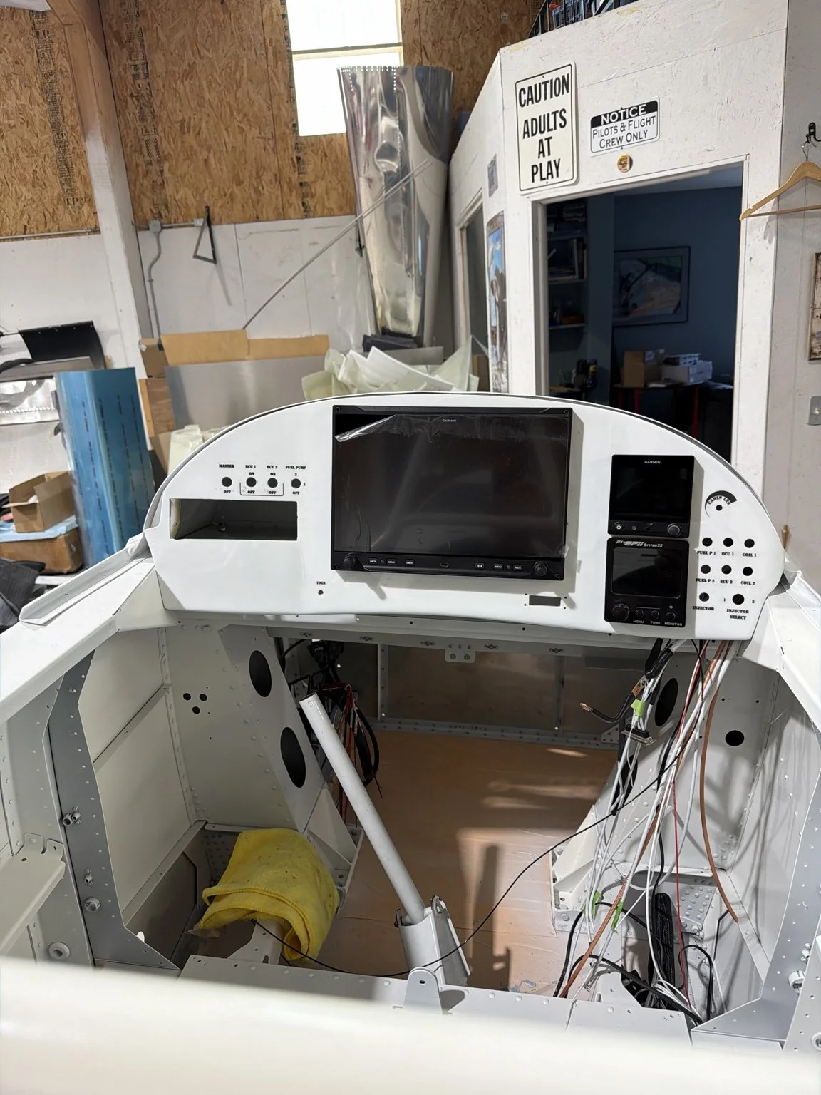 White custom-molded RV-8 panel during installation, with centered Garmin display, equipment on the right, and wiring in progress