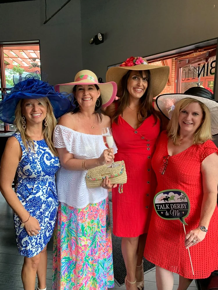 Guests dressed in Kentucky Derby hats and dresses at Bin 110 in Cornelius, NC