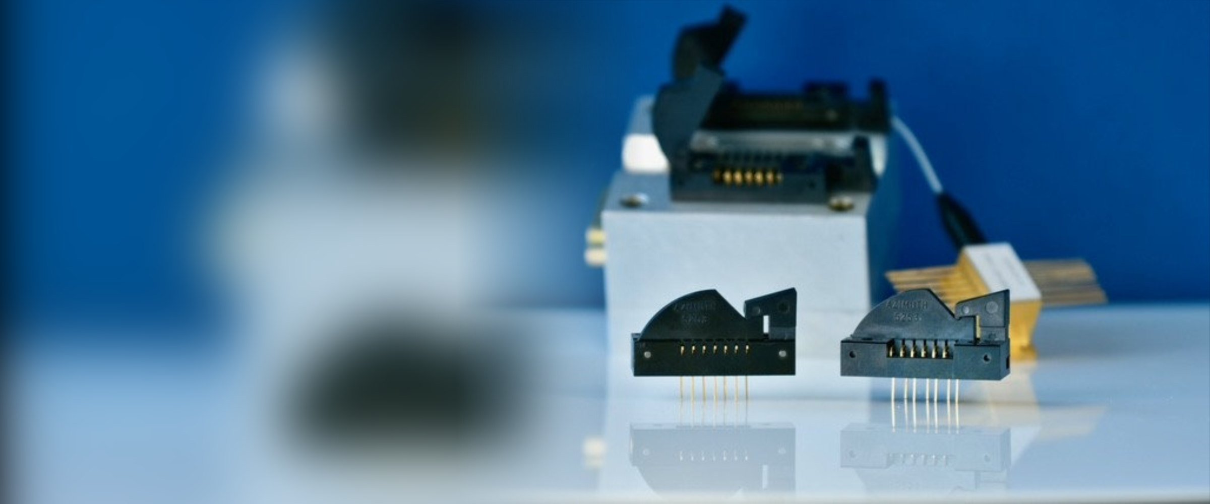 Two Azimuth Electronics 5253 Series single in-line flat package sockets with gold pins on a reflective surface