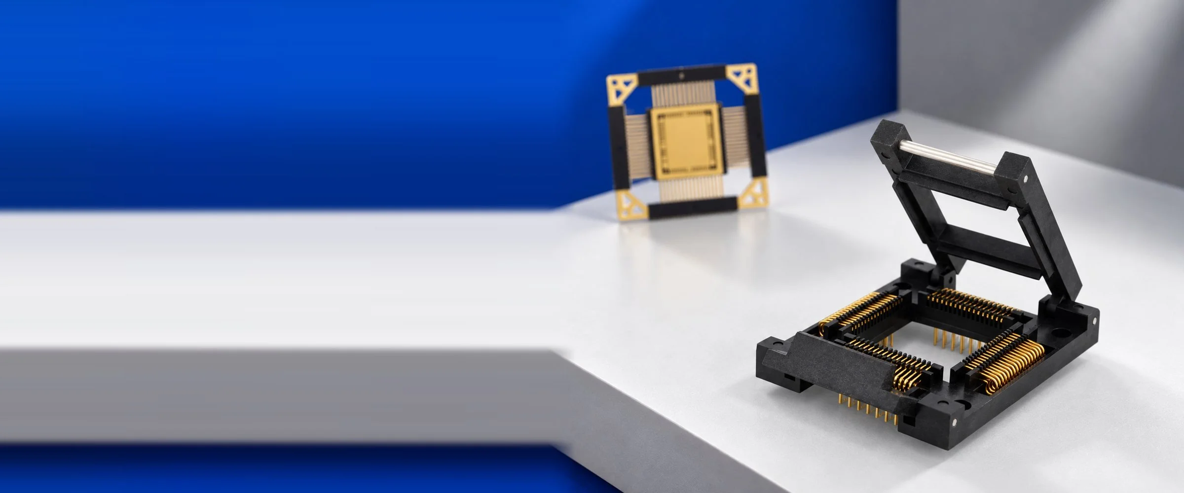 Azimuth Electronics hinged-lid IC socket with gold spring contacts, with a gold leaded device carrier in the background