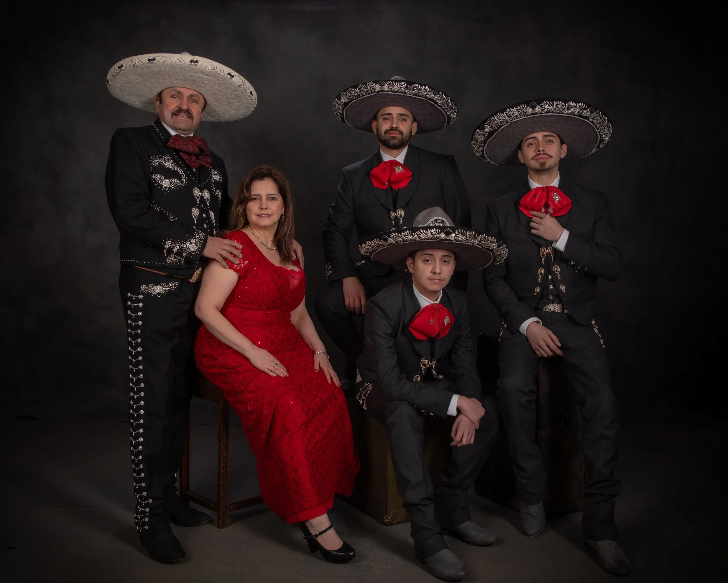A family in traditional charro suits and sombreros with red dresses