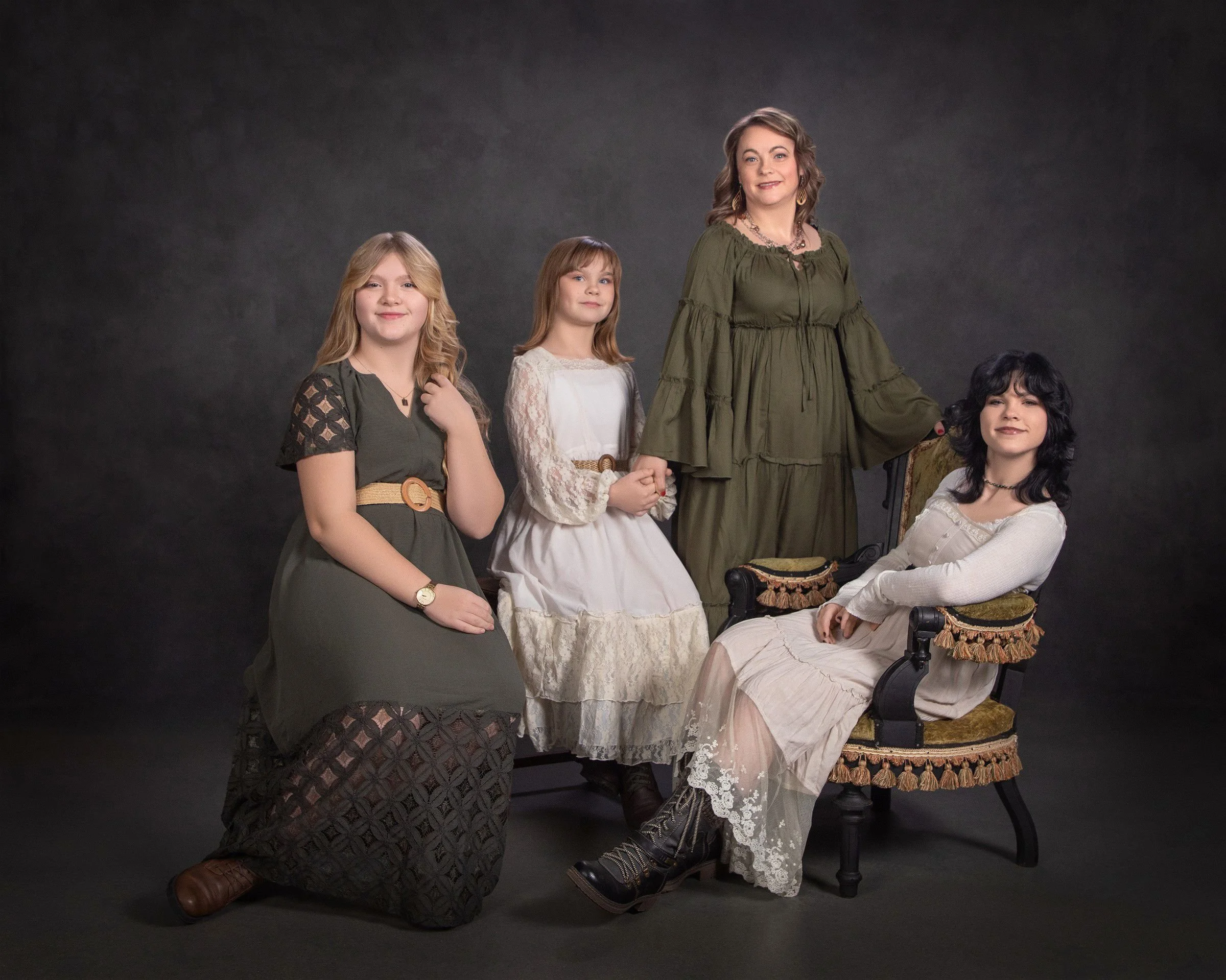 Family portrait of a mother and three daughters in layered earthy tones including white lace, olive green, and warm neutrals