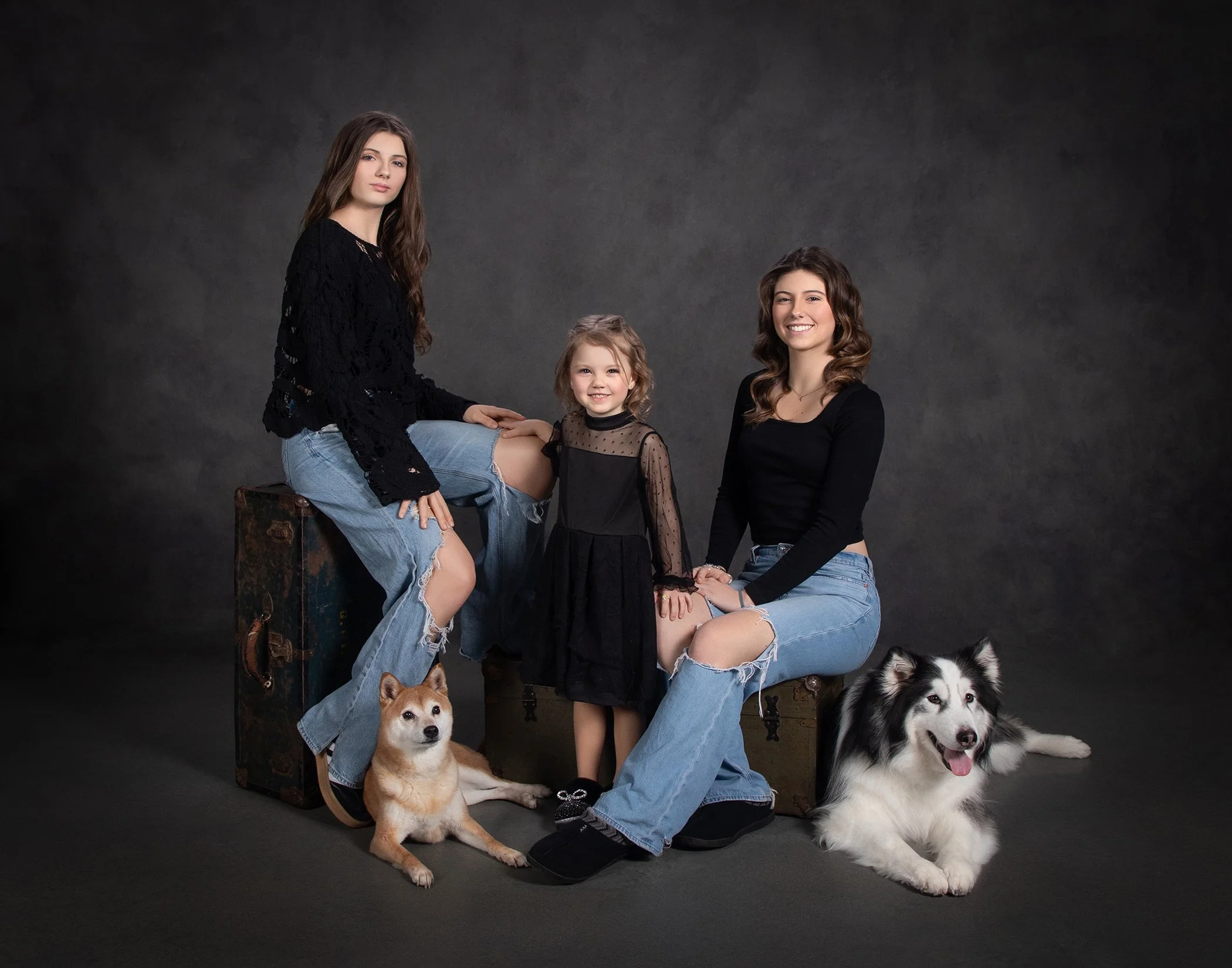 Three family members in relaxed evening wear with their two husky dogs