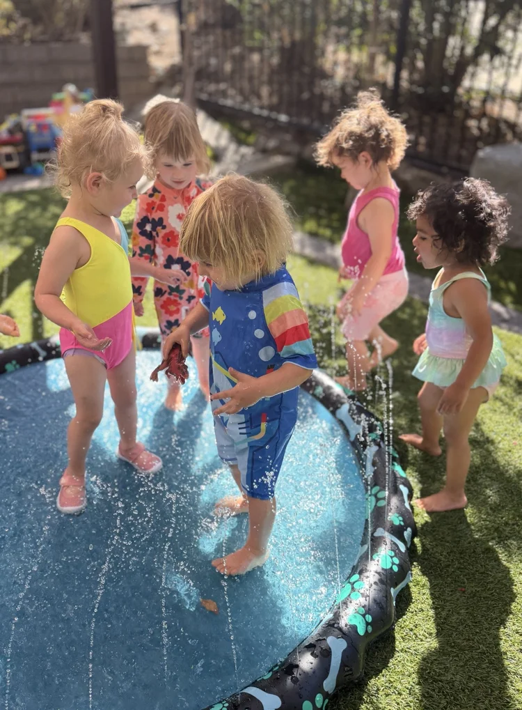 Children splashing together around a circular outdoor sprinkler pad