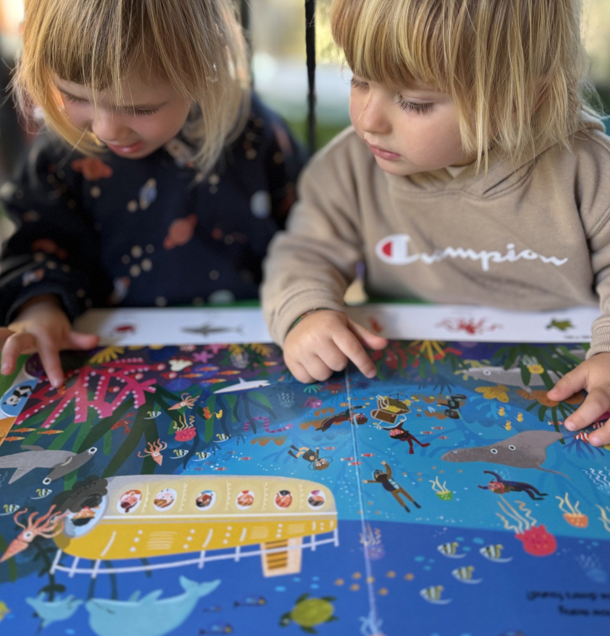 Two children looking closely at an illustrated book together