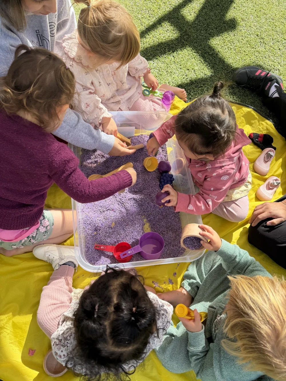 Children exploring a colorful sensory tray outdoors together