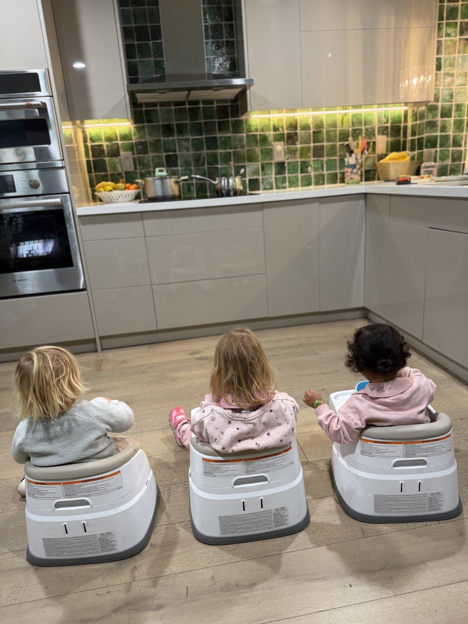 Three young children sitting together in Mila-Ma’s kitchen
