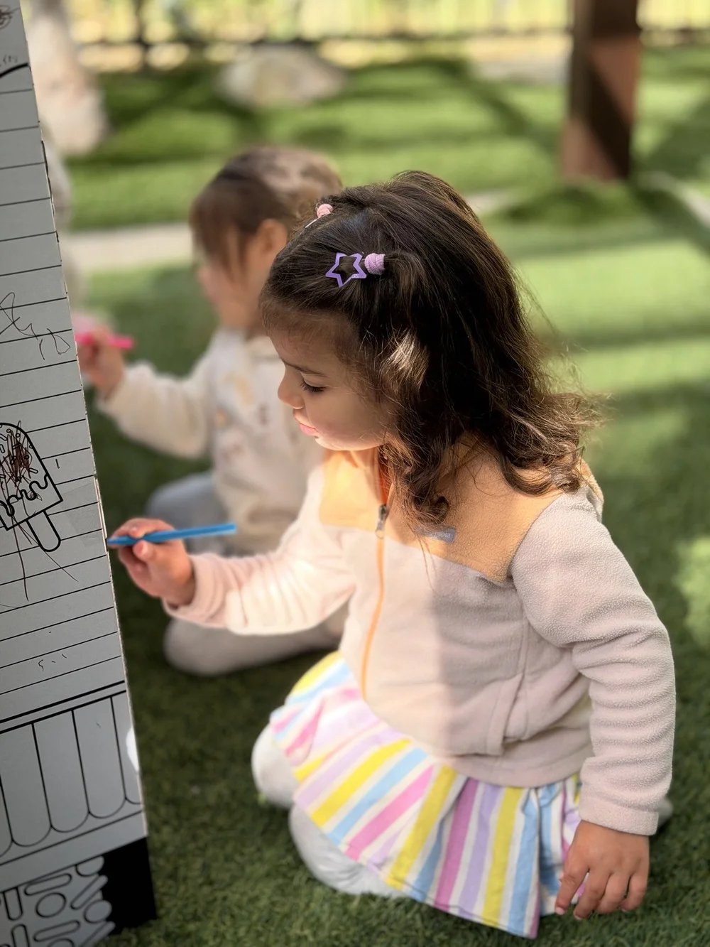 Children drawing together on an outdoor activity board