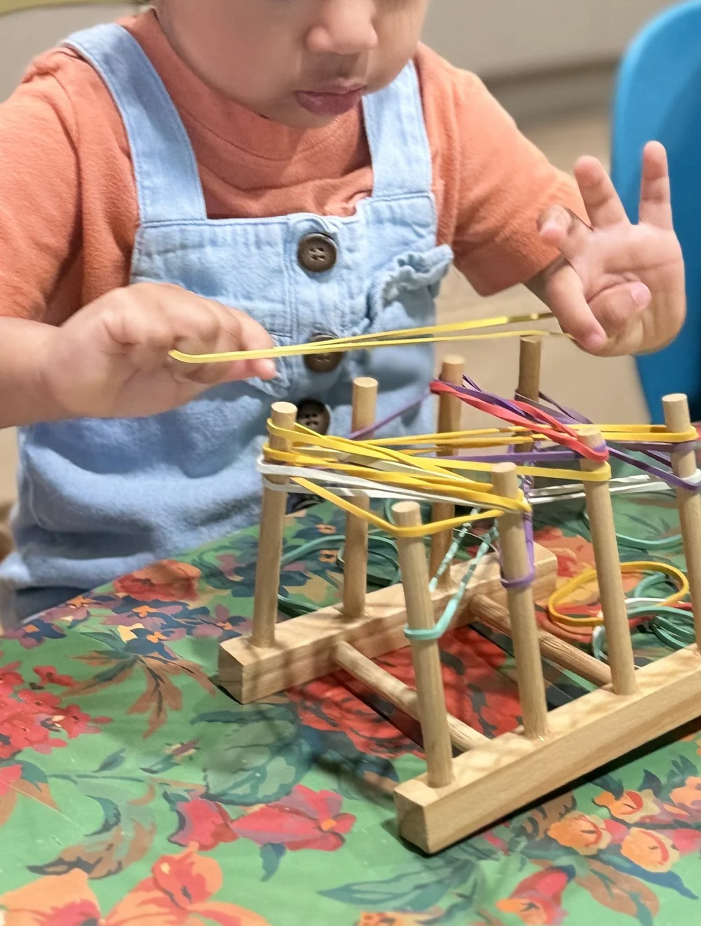 A child placing colorful sticks into a wooden activity frame