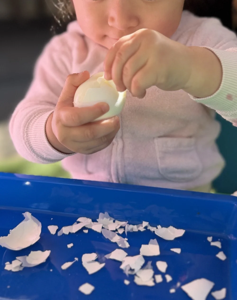 A child carefully peeling a hard-boiled egg