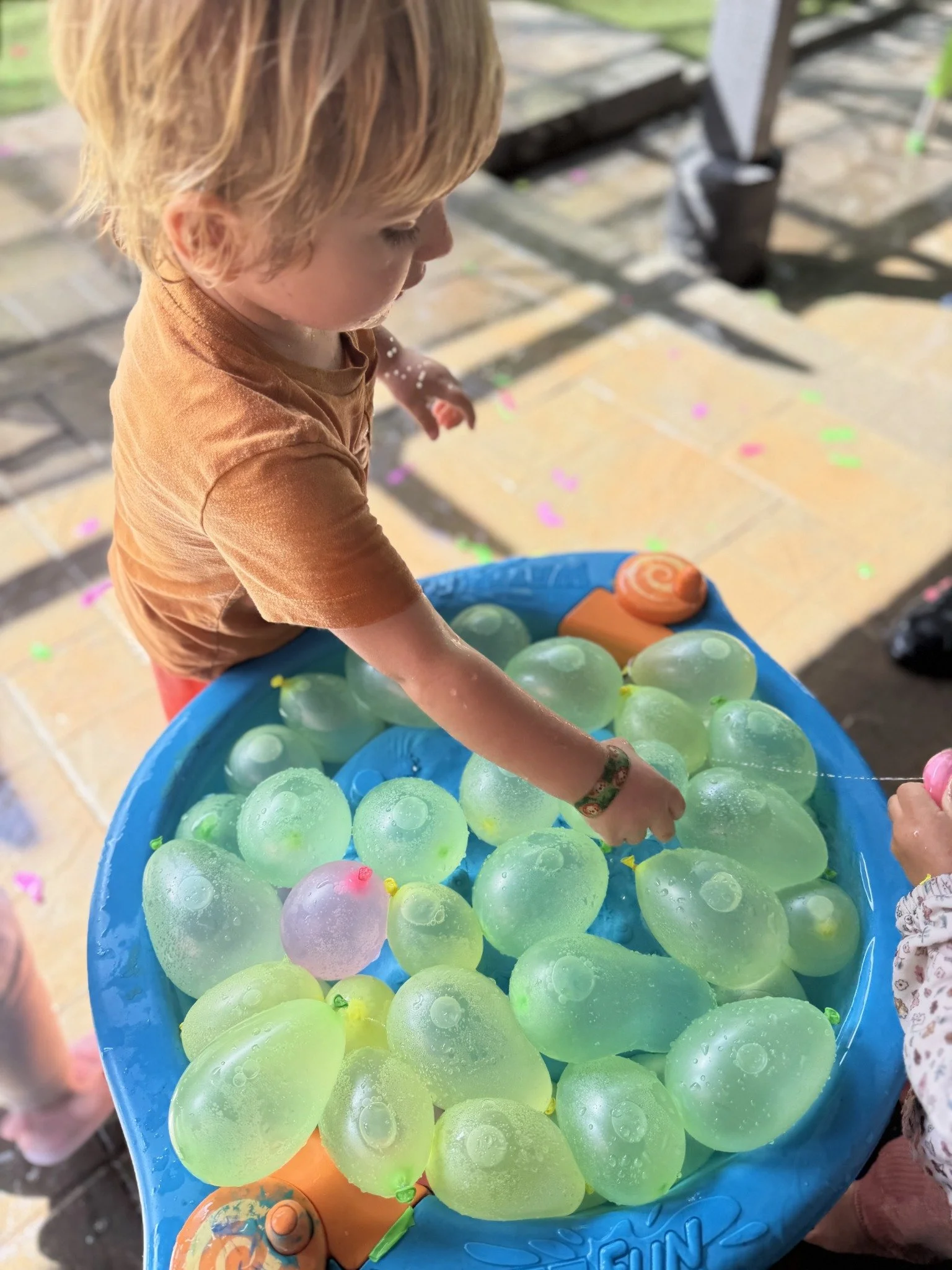 A child exploring a colorful outdoor sensory tray