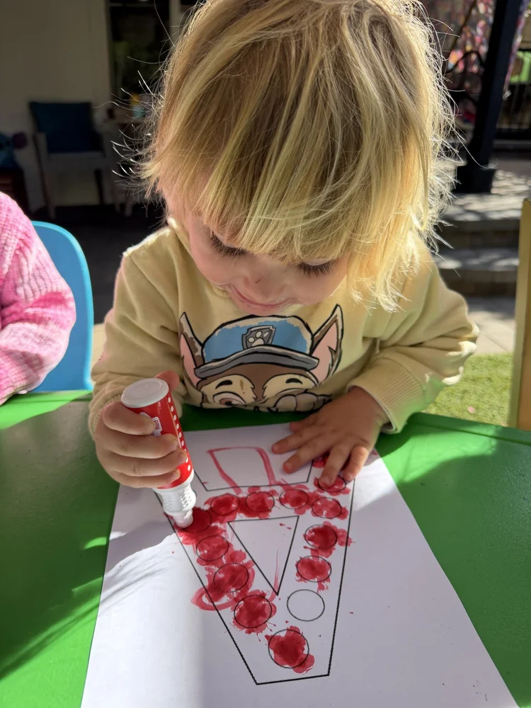 A child making red dots on paper with a paint marker