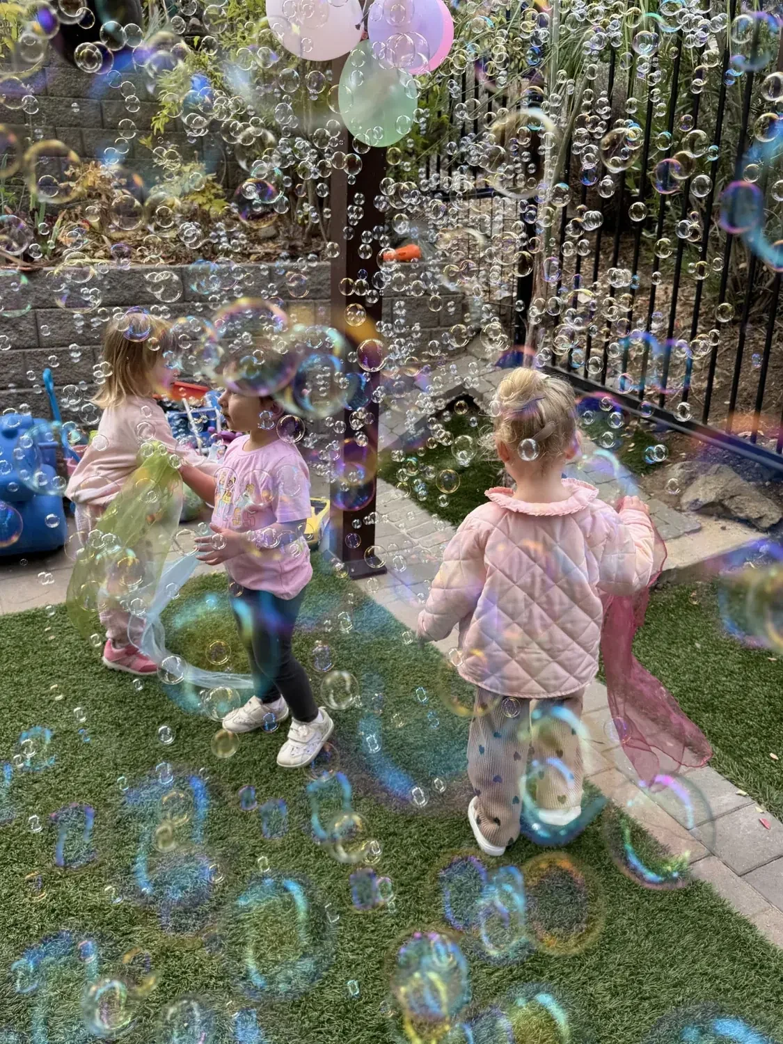 Children playing among bubbles and colorful scarves in the Mila-Ma garden