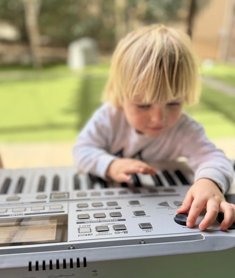 A child exploring the keys of an electronic keyboard