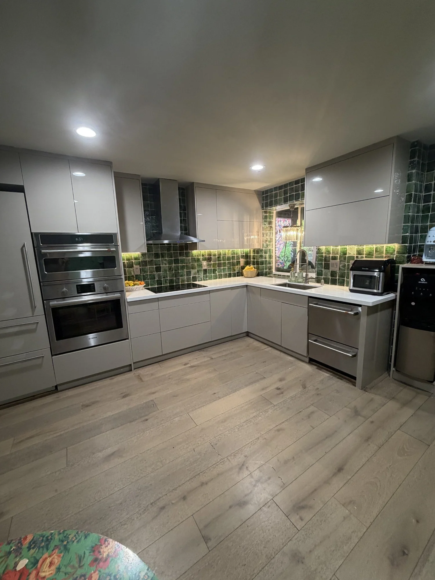 Mila-Ma kitchen with green tiled walls, pale cabinets and a garden window