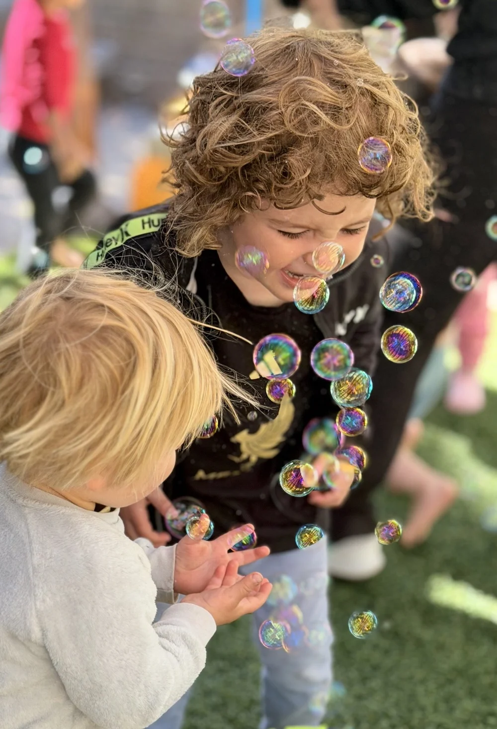 Children watching floating bubbles with delight in the garden
