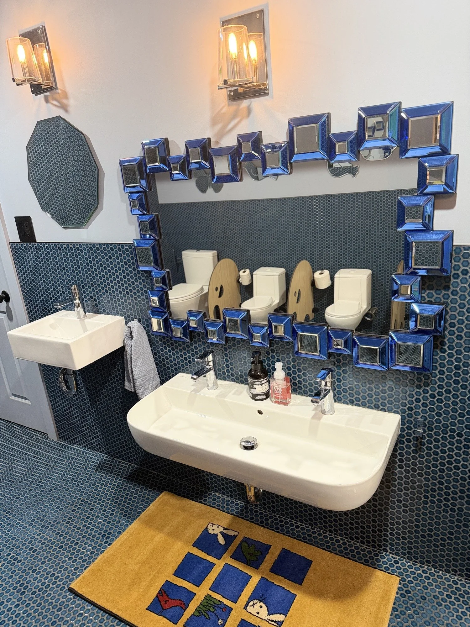 Low handwashing sink beneath a blue framed mirror in the Mila-Ma bathroom