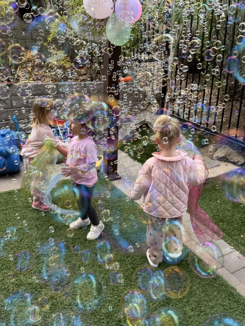 Children playing among bubbles and colorful scarves in the Mila-Ma garden