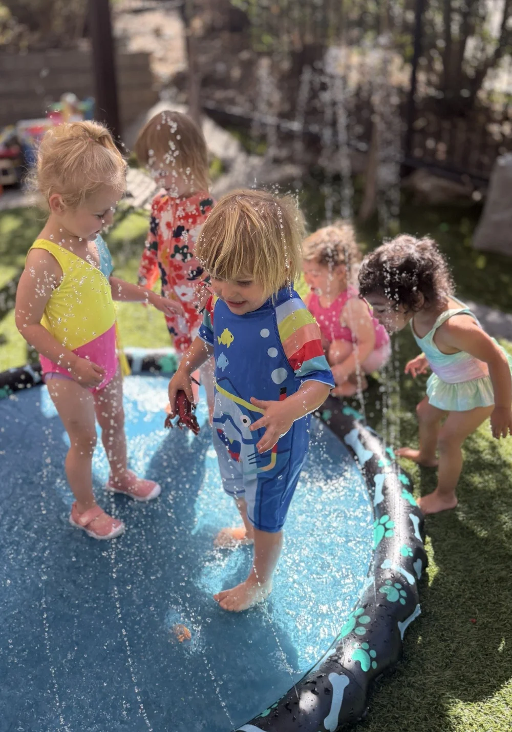 Children splashing together on a blue water play mat