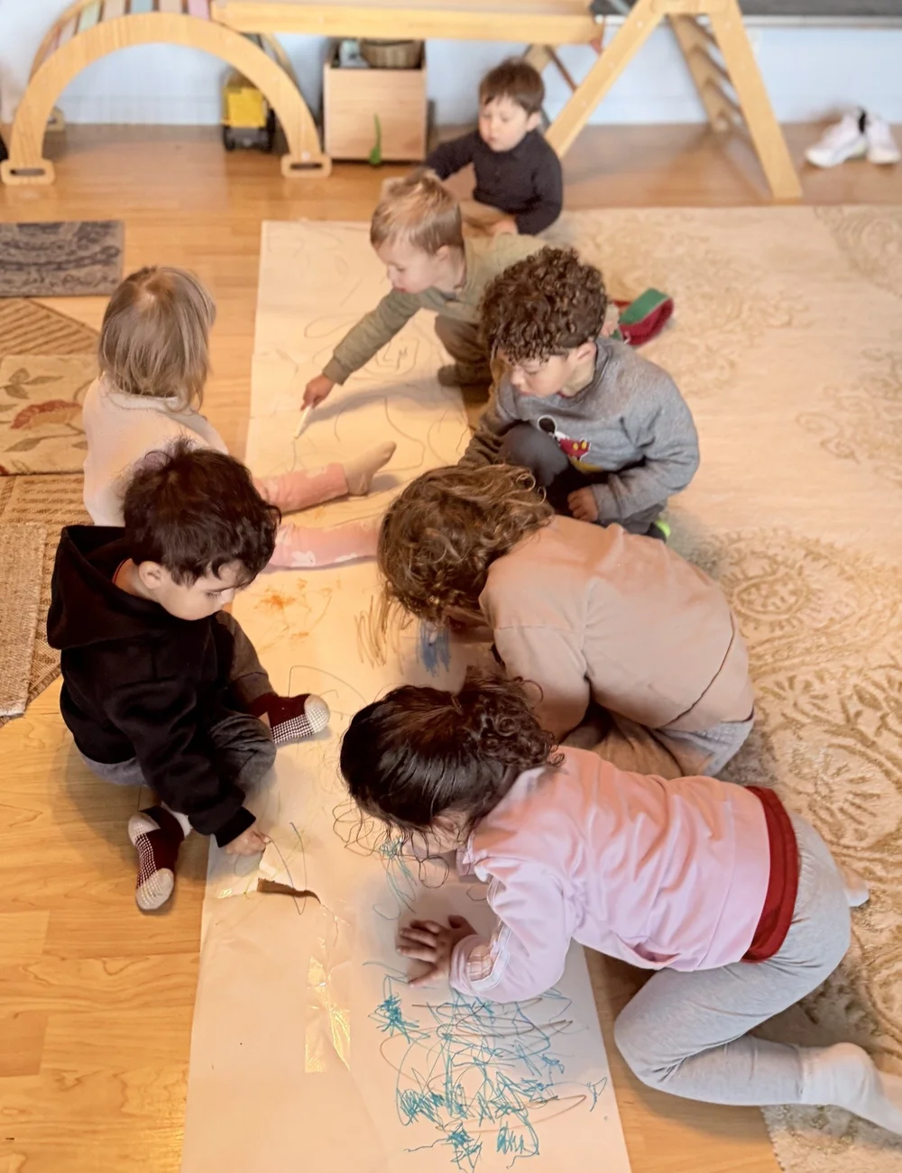 Children making a shared drawing on a long piece of paper