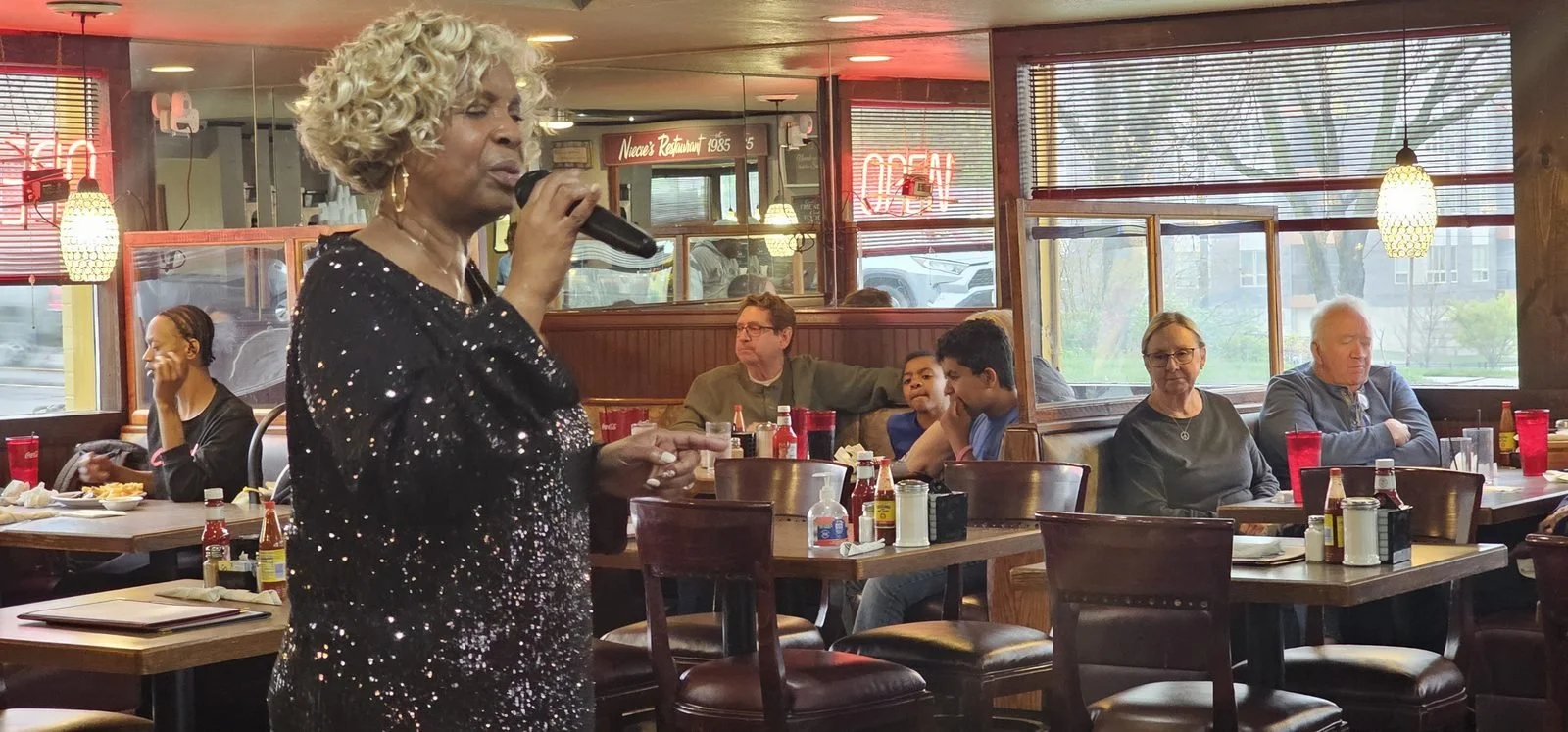 A singer performs beside diners seated near the windows at Niecie’s.
