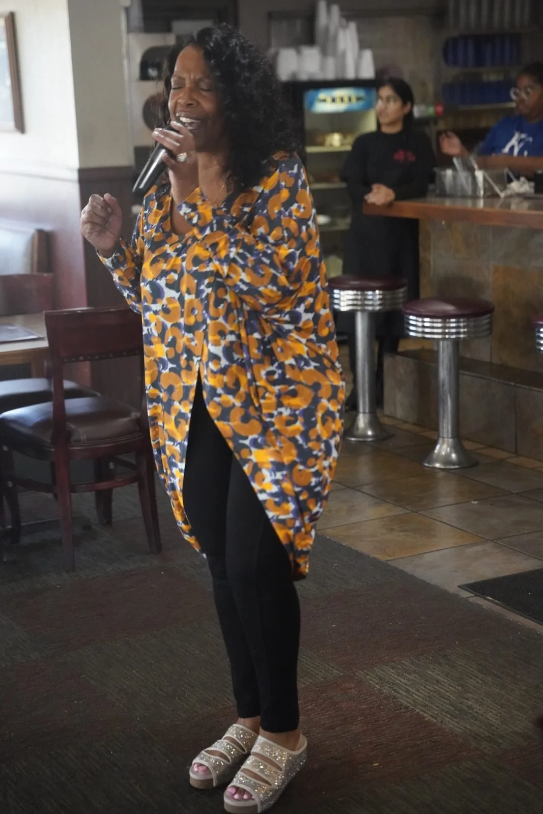 A singer holds a microphone while standing in Niecie’s dining room.