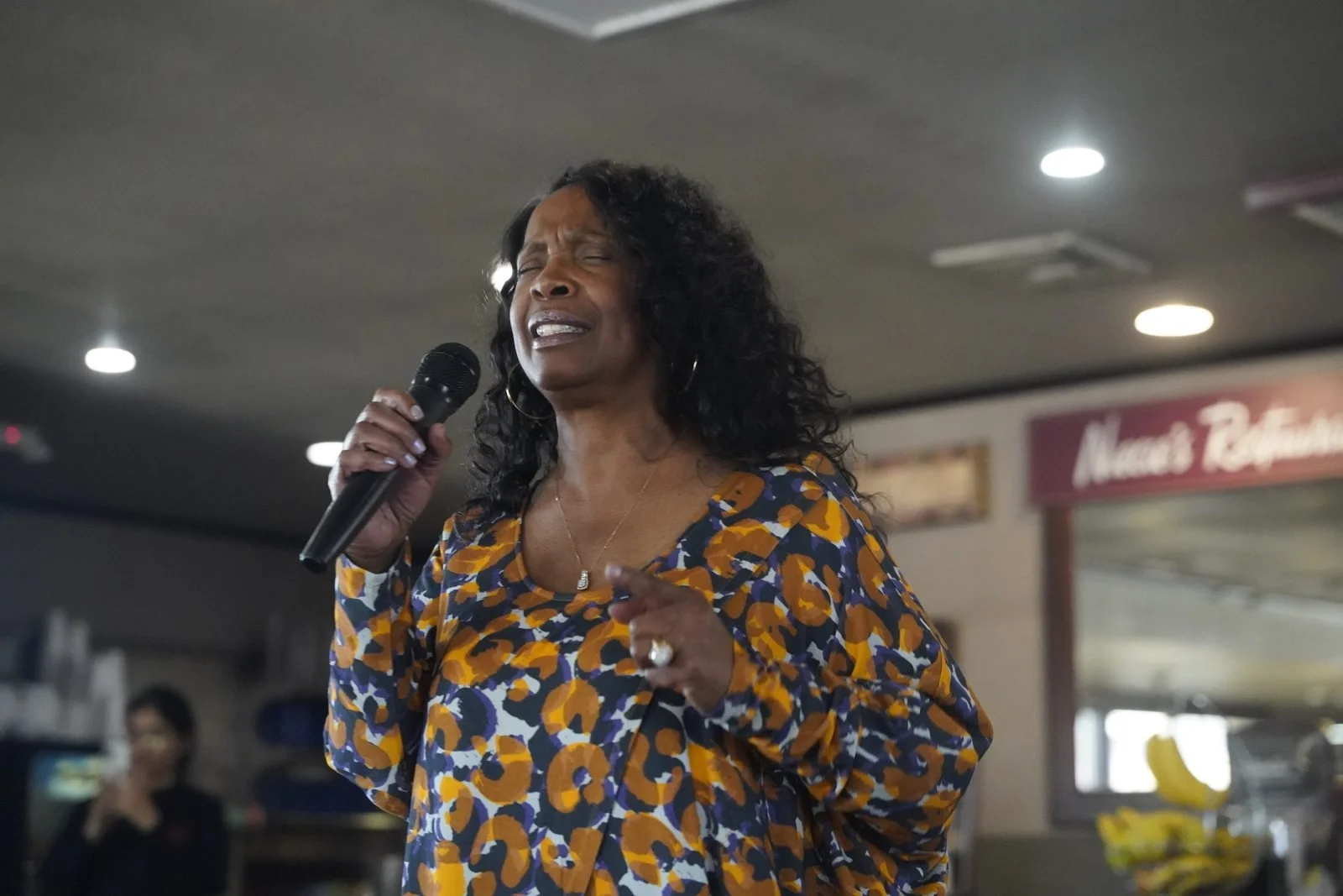 A singer in an orange and blue patterned top performs with a microphone at Niecie’s.