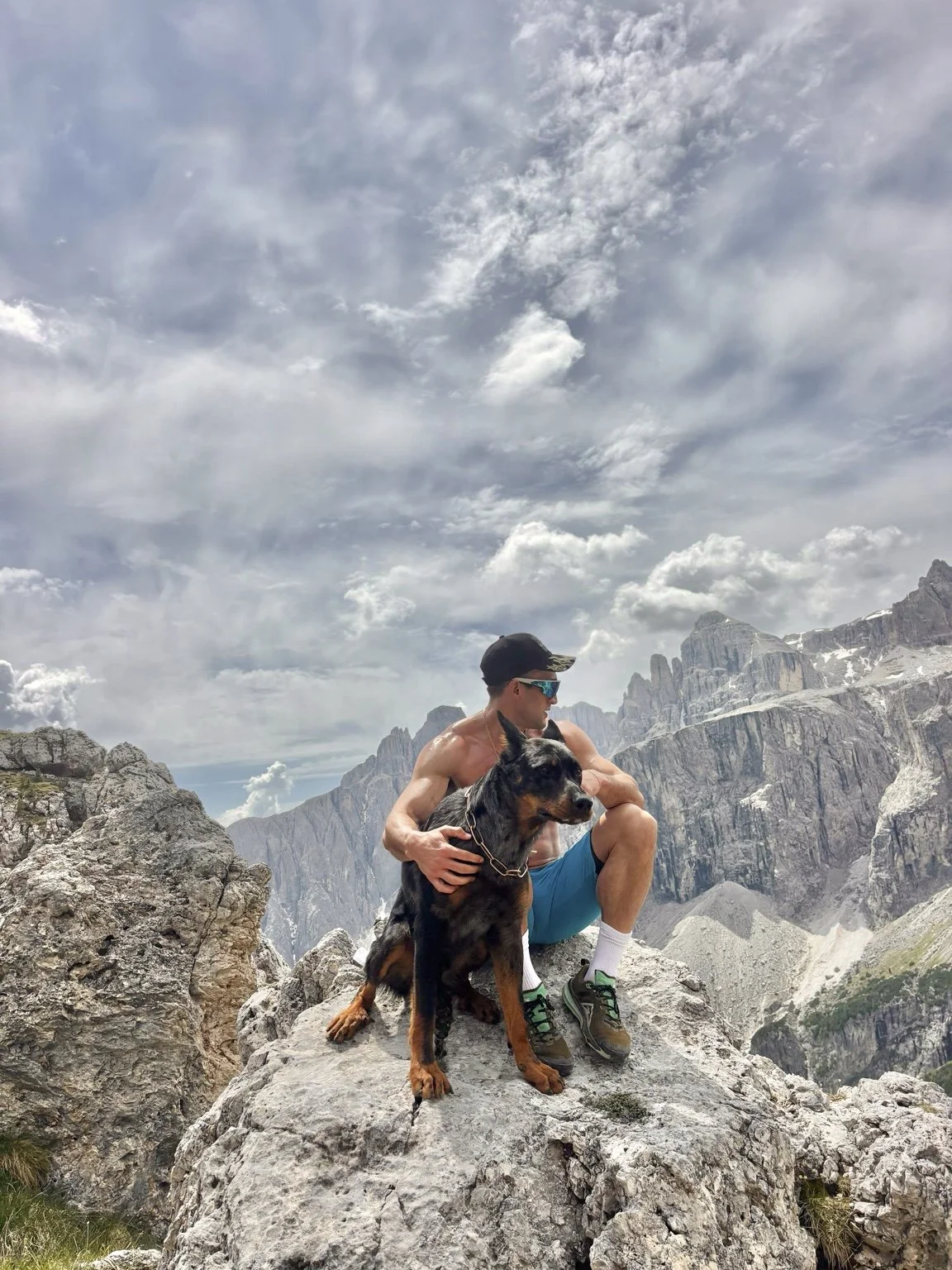 A Beauceron and its owner taking in a dramatic mountain summit.