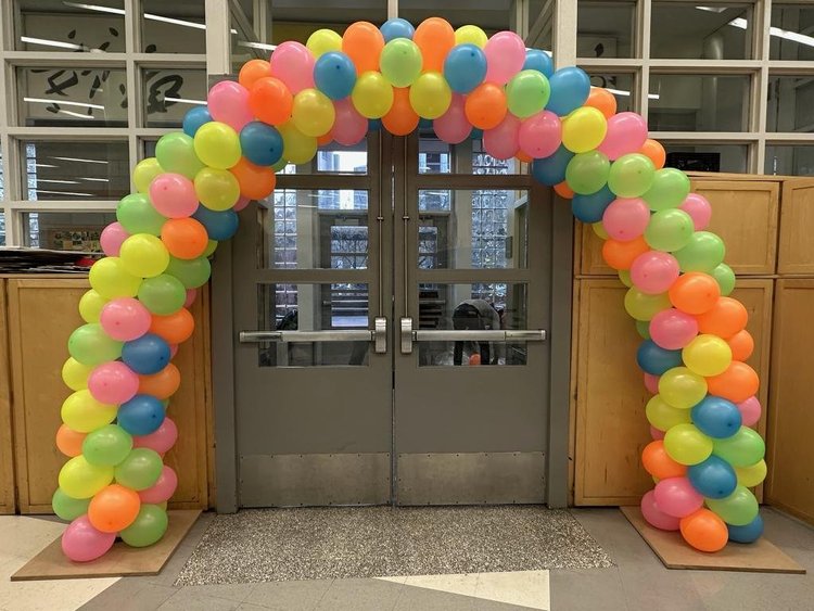 Neon balloon arch glowing under black light at a Manhattan glow party
