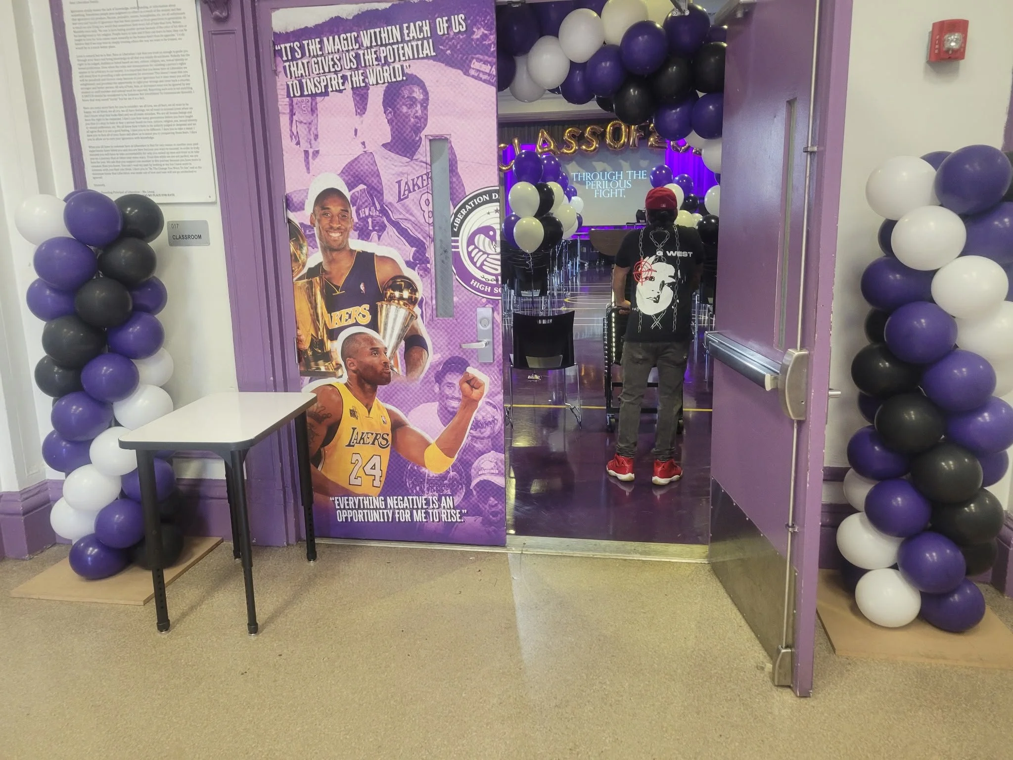 Purple black and white spiral balloon columns framing a Brooklyn high school graduation entrance NYC