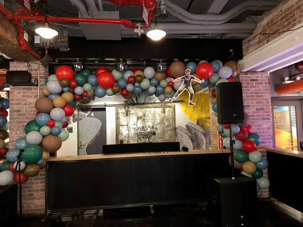 Organic earth-tone balloon arch framing the DJ stage at a bar mitzvah at Chelsea Market NYC