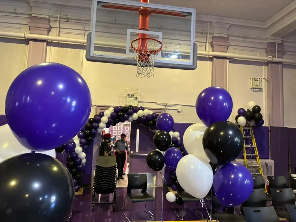 Balloon bouquets and graduation decor setup in a Brooklyn high school gym NYC