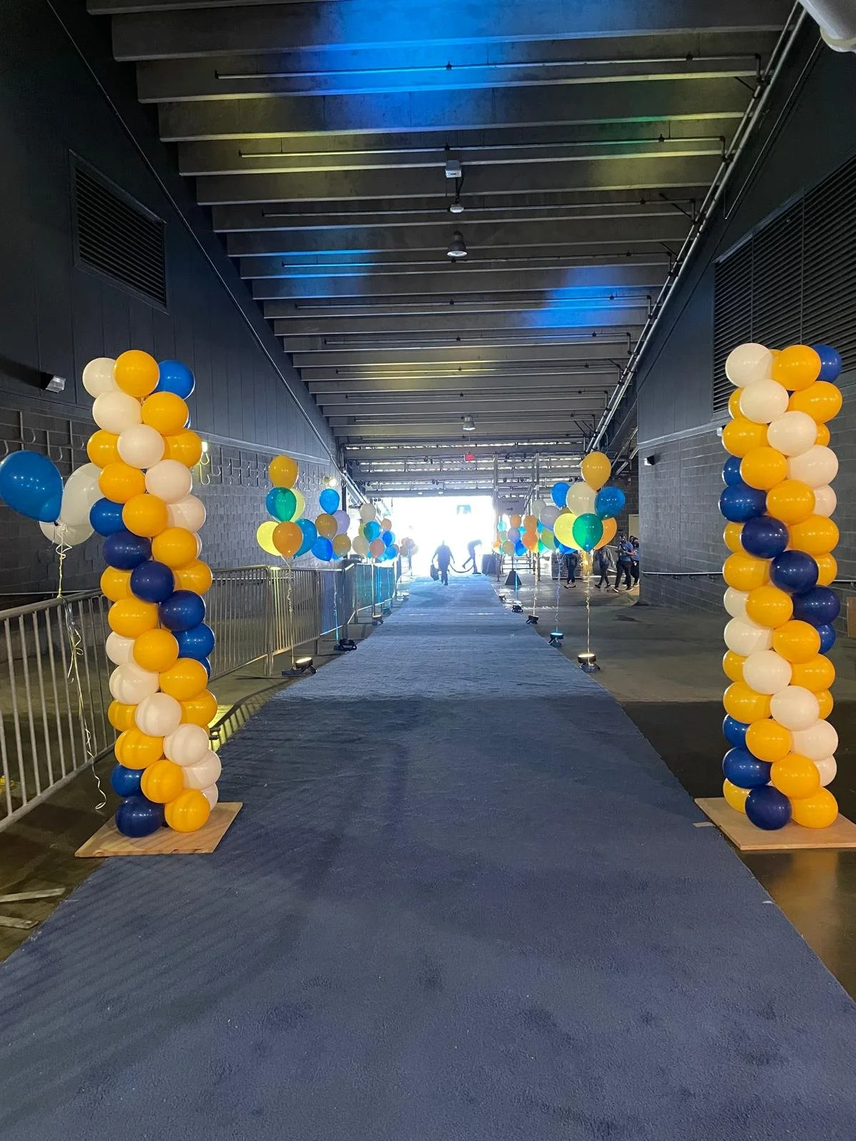 Tall blue gold and white graduation balloon columns at MetLife Stadium entrance East Rutherford NJ