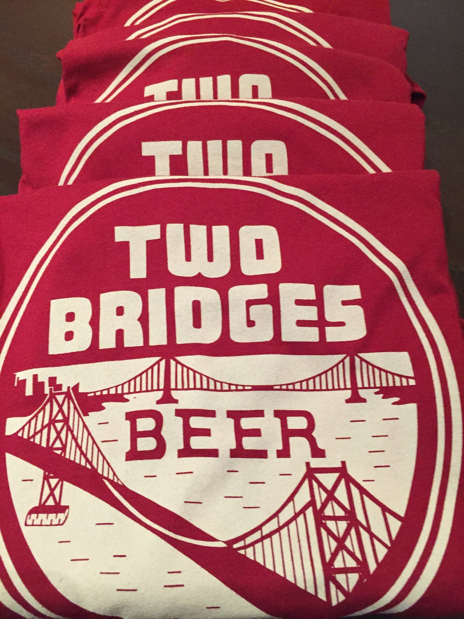 A stack of red Two Bridges Beer tees