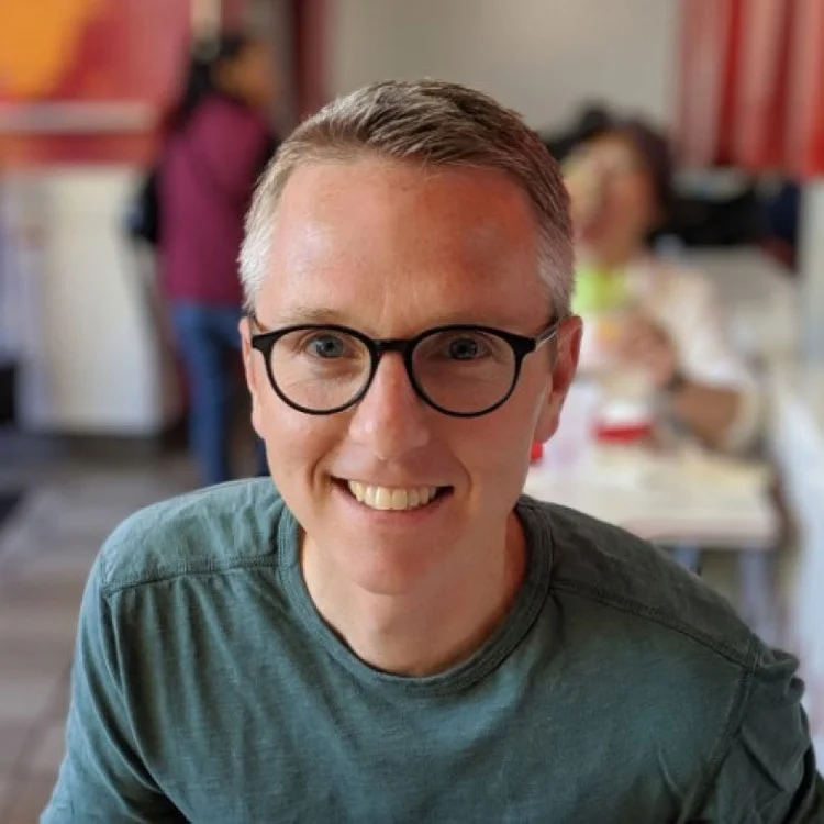 Doug Neumann wearing glasses and a green shirt. 