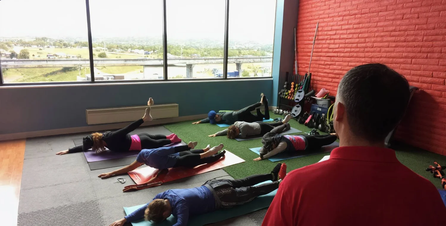 A small group class doing a guided stretch on exercise mats
