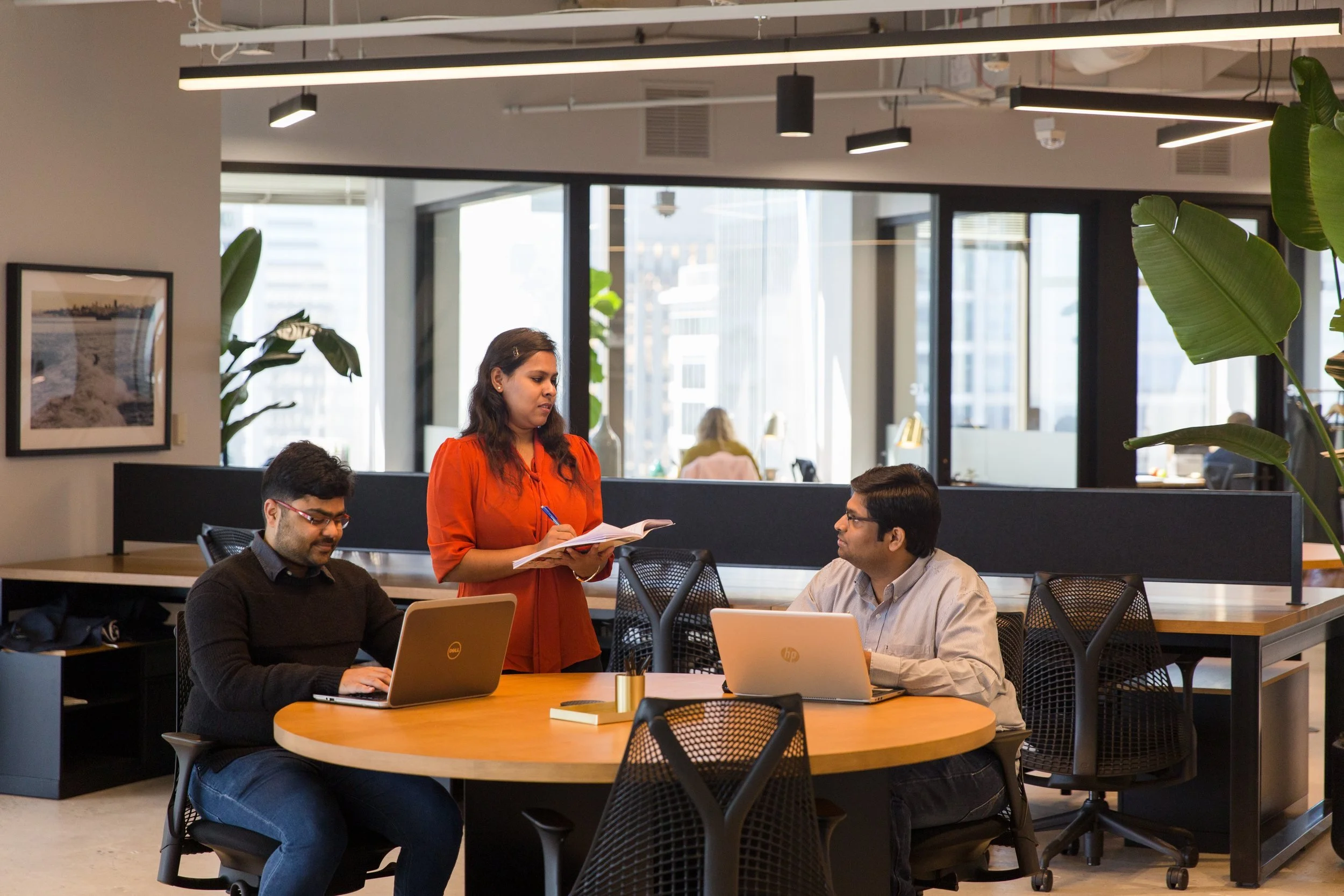 Team members working on laptops and reviewing notes together in a bright office
